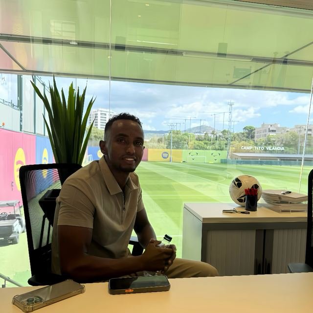 Nasir Hassan at a desk overlooking football training pitches